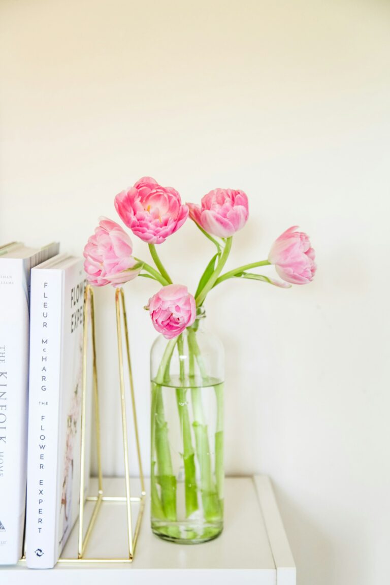 Pink pastel tulips in glass vase next to books
